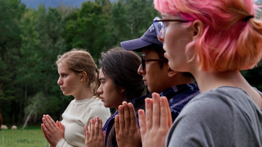 Students meditate together at a serene outdoor spot on campus.
