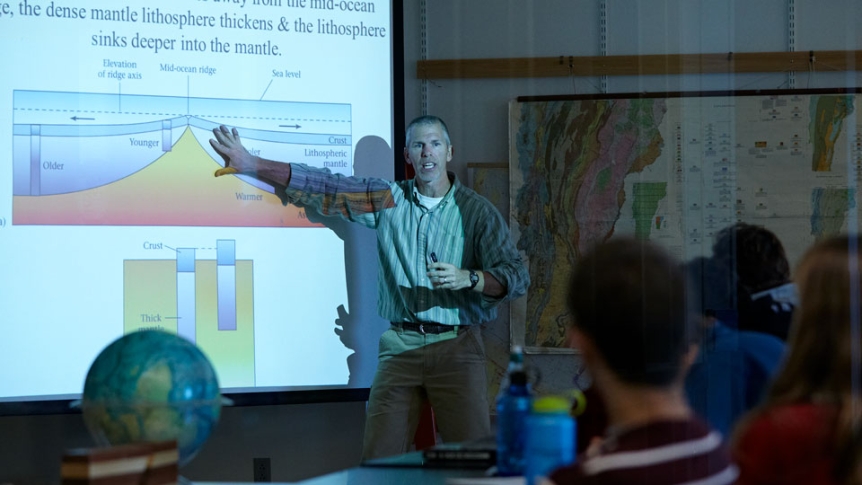 A professor presents a slideshow to his seminar students.