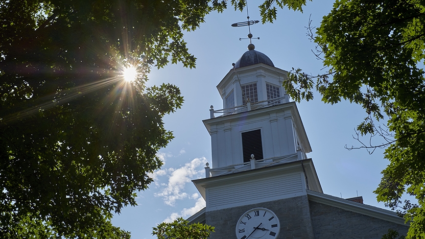 Old Chapel on Middlebury's Campus with sun shining in background.
