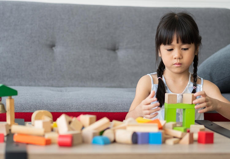 Asian little girl playing with colorful toy blocks