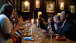 BLSE students dine at a table by candlelight in a woodpaneled room