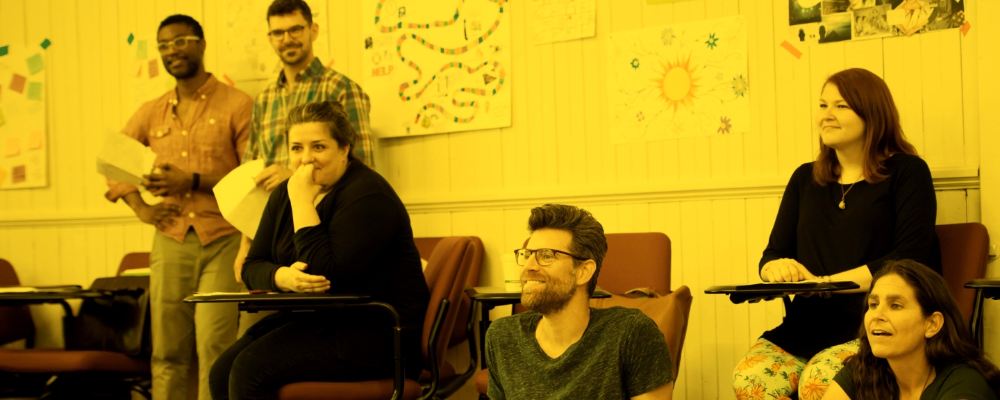 Six School of English students sitting and standing in a classroom.