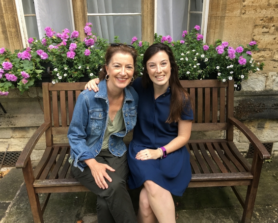 Two female students sit outdoors on a bench.