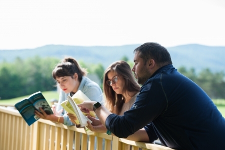 Students lean against the railing, reading books