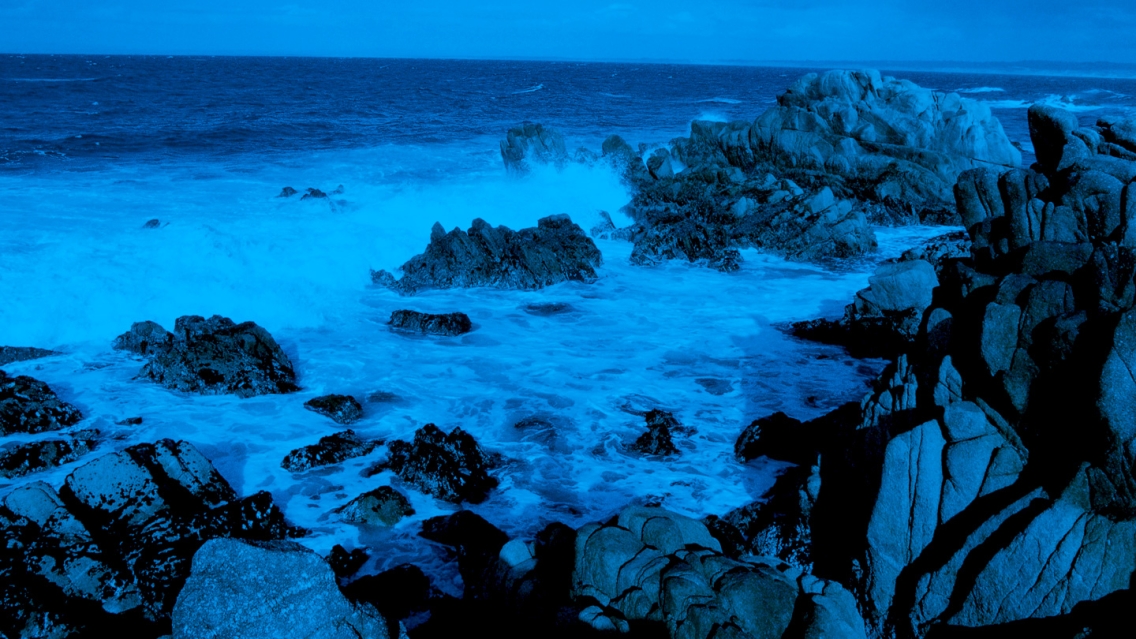 Water crashing against rocks on the beach in Monterey, CA