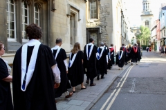 BLSE at Oxford graduates walk down the street in their caps and gowns.