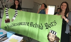 Three students hold a homemade Shakespeare banner.