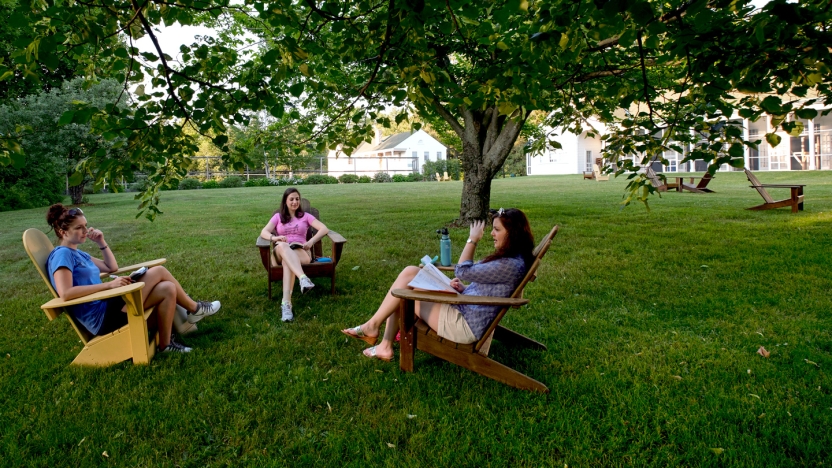 Three female Bread Loaf School of English students sitting outside in adirondack chairs.