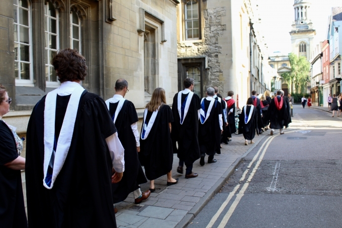 BLSE at Oxford graduates walk down the street in their caps and gowns.