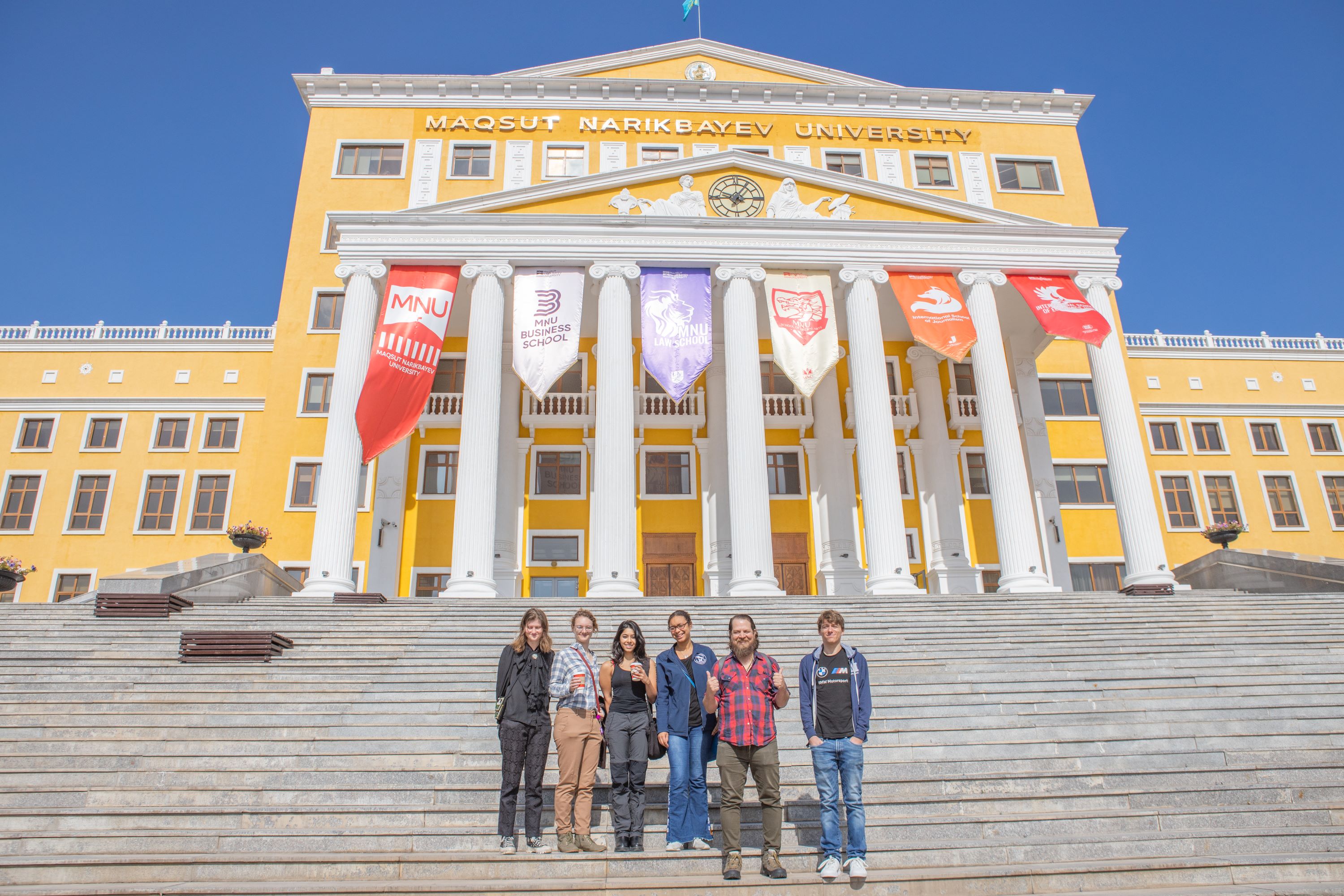 Students standing on the steps of a yellow building