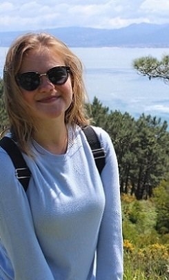 A student stands in front of a lake