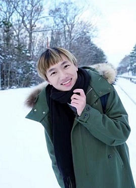 A student stands in the snow, wearing a winter jacket