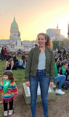 A student stands outside with a crowd of people during sunset