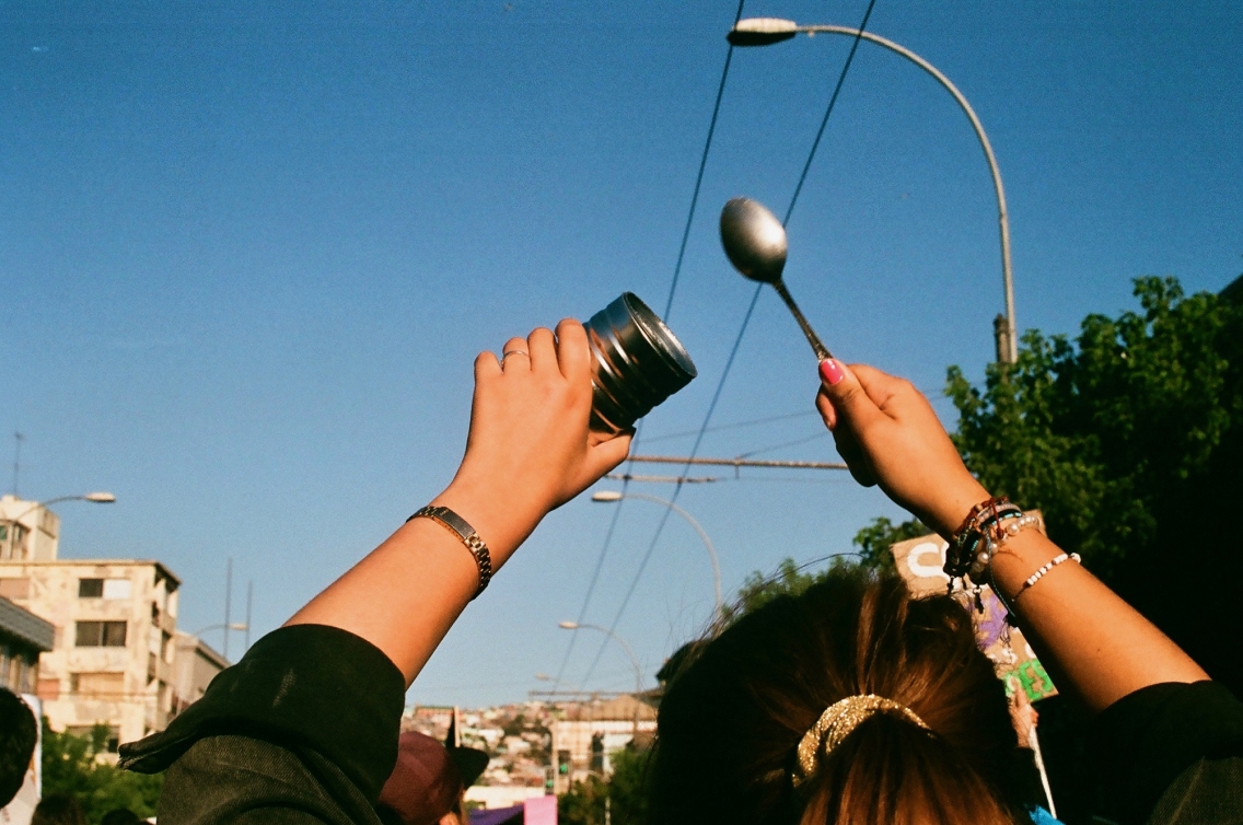 A woman at a protest with a can and a spoon in the air