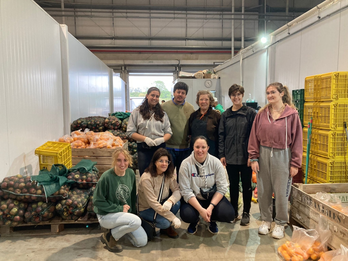 Students in front of bins and bags of food