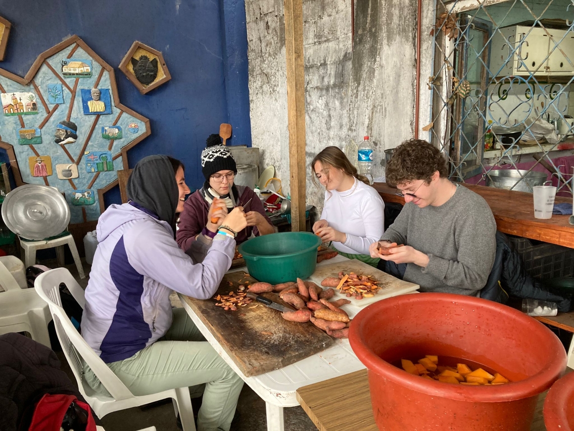 Students peeling potatoes around a table