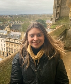 Student smiling in front of mossy stone architecture