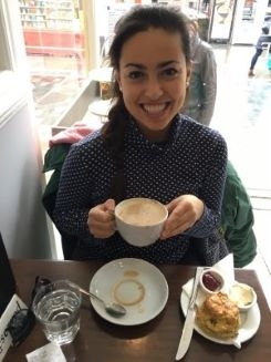 Student smiling at a cafe, cup in hand