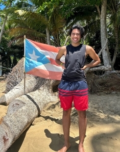 Student smiling in front of the Puerto Rican flag