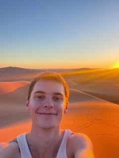 Student taking a selfie at sunset amongst sand dunes