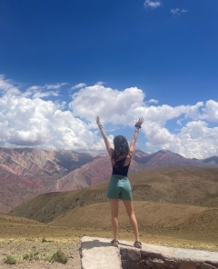 Student with arms outstretched in front of a mountain range