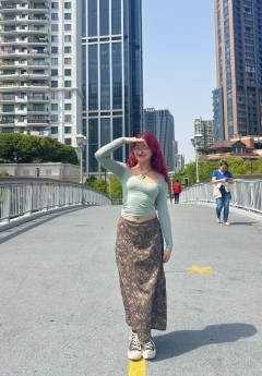 Student with red hair smiling in front of tall buildings