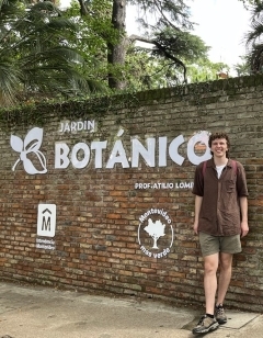 Student smiling in front of a botanical garden sign
