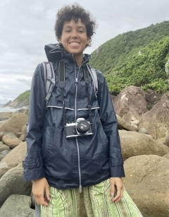 Student smiling in front of rocks wearing a camera