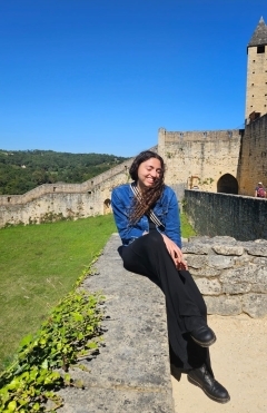 Student in a blue jacket smiling in front of a blue sky