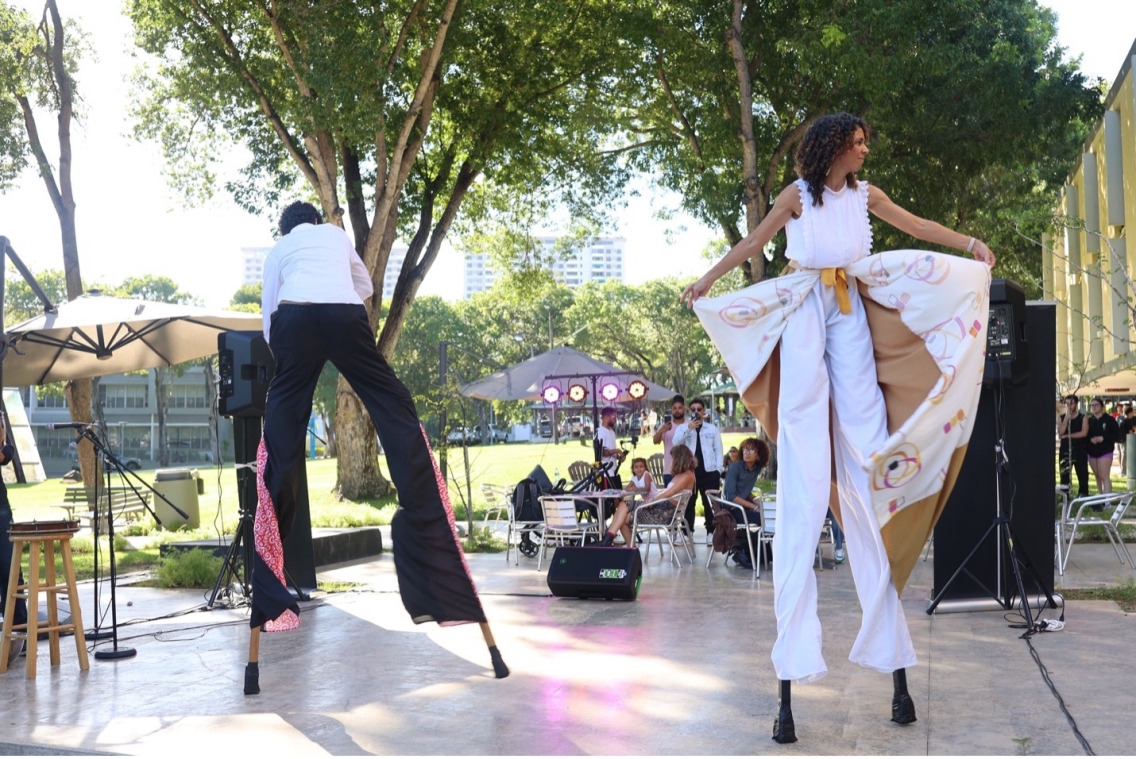 Two people on stilts on a public stage space