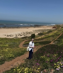 Student smiling in front of a beach and blue sky