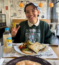 Student smiling and giving a peace sign with a plate of food