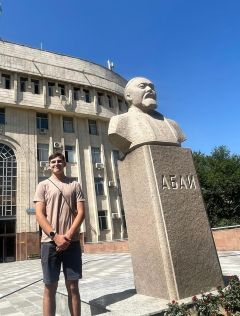 Student posing next to a building and statue