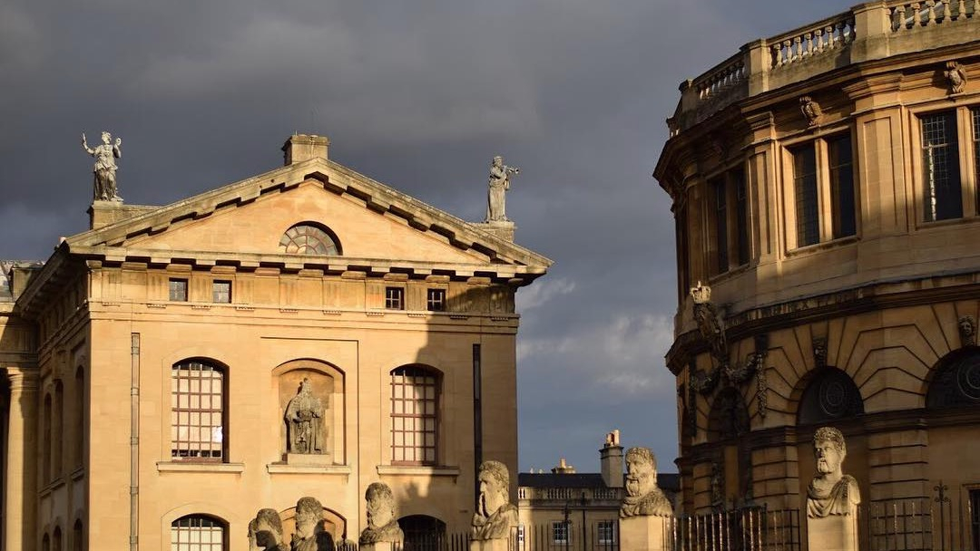 The Clarendon Building and the Sheldonian Theatre are offset by a dark sky that threatens rain, even though sun is illuminating the golden stone.