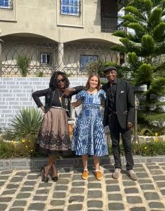 A student in a blue dress posing with their host parents