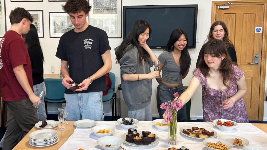 Students laugh and select which cupcake to eat next at the Seminar Essay Submission party held in the Room of Requirement at St Michael's Hall.