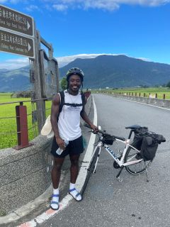 Student with a bike posing with a mountain in the distance