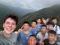 Student posing in the mountains with a group of children