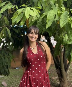 Student smiling in front of a leafy tree