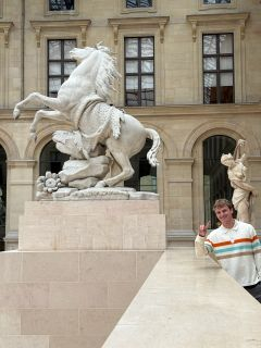 Student smiling in a museum next to a large horse sculpture