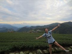 Student posing in front of a green field and mountains