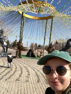 Student posing in front of a flower filled sculpture