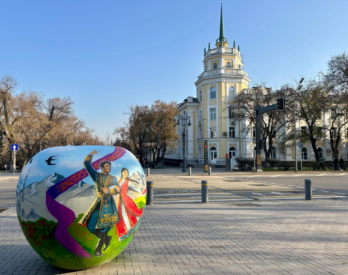 A painted apple statue with a church in the background