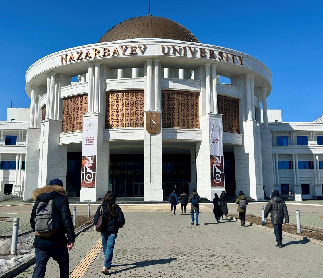 Students walk towards a building with Nazarbayev University signage