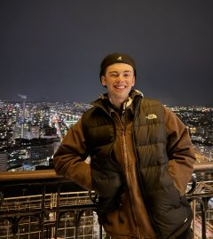 Student smiling against a dark city scape