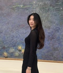 Student in black clothing posing in front of a blue painting