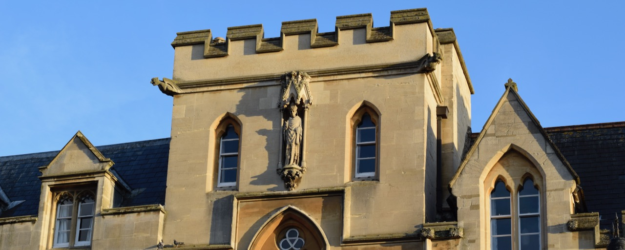 A golden stoned Oxford college against a blue sky.
