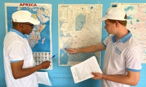 A student points to a map with a professor looking on.