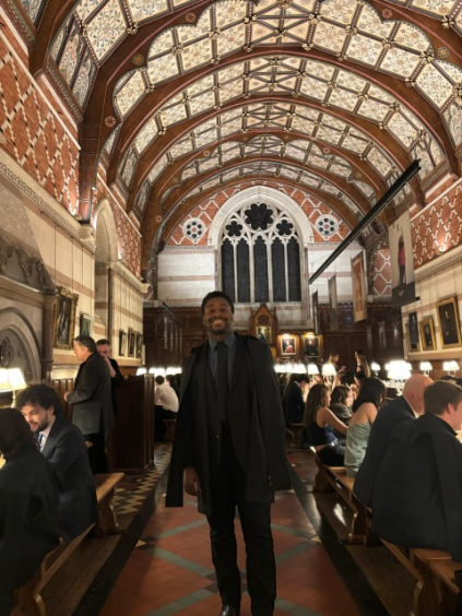 A student stands in an ornate dining hall