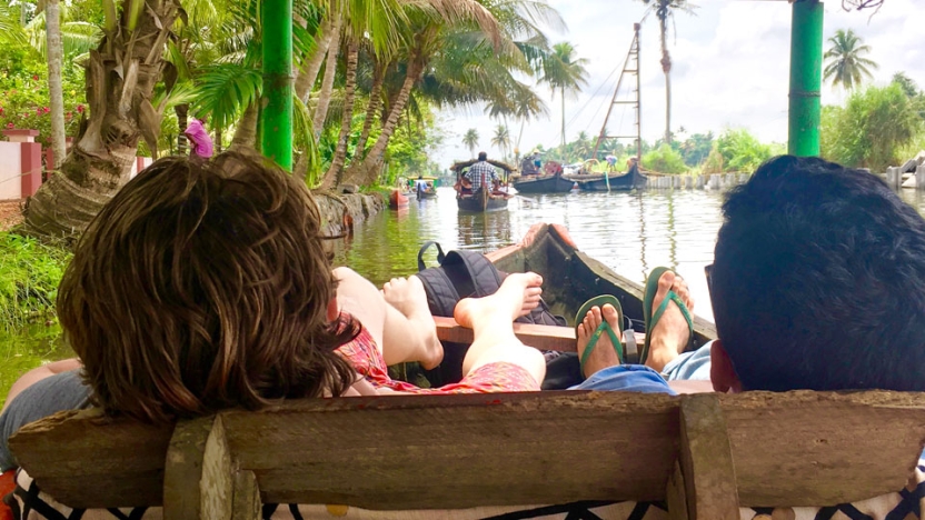 Students sitting in boat on water with feet hanging off side of boat